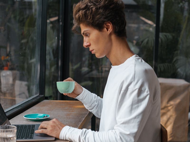 Молодой предприниматель работает за ноутбуком в уютном кафе